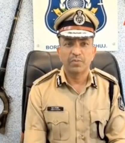 Chirag Koradia in uniform and peaked cap at the Border Range office in Bhuj, seated in front of the range signboard.